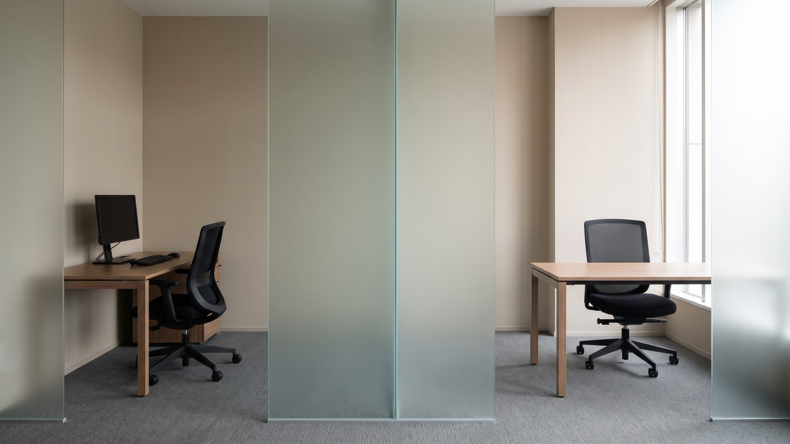 Two separate empty office workspaces divided by a frosted glass partition
